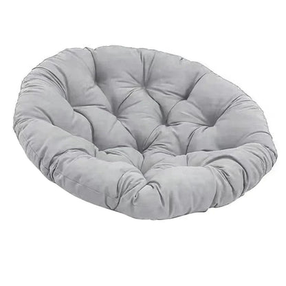 Coussin décoratif rond en velours gris, installé sur un canapé, offrant confort et style moderne