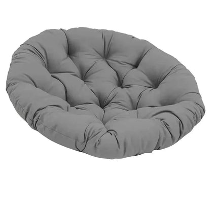 Coussin décoratif rond en tissu gris, rembourré et matelassé, posé sur une surface extérieure