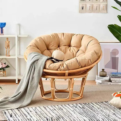 Coussin décoratif rond en tissu beige sur un fauteuil en rotin dans un salon moderne