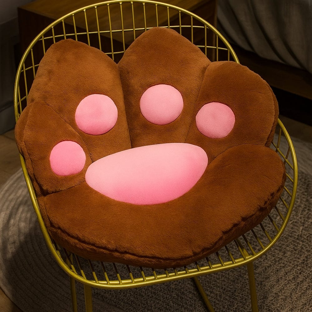 Coussin en forme de patte de chat, marron et rose, posé sur une chaise dorée dans un salon moderne