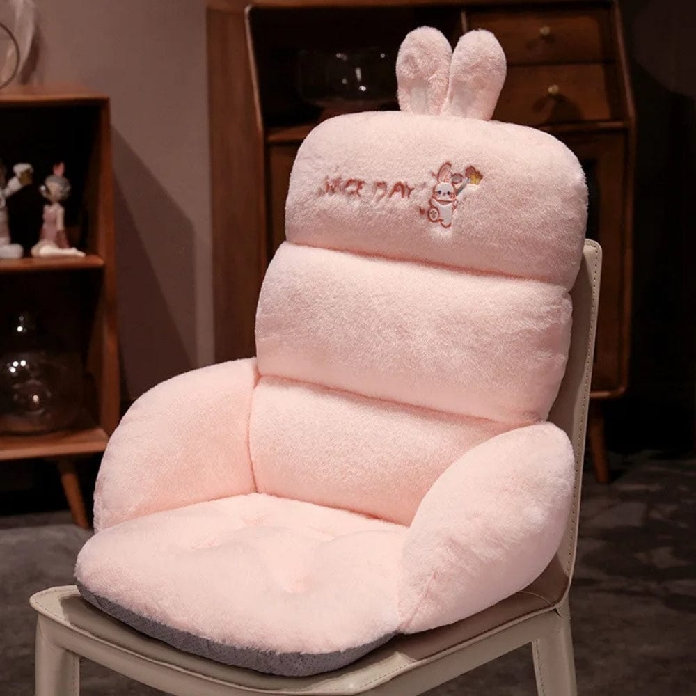Coussin déco en peluche rose avec oreilles de lapin, posé sur une chaise de bureau dans un intérieur chaleureux
