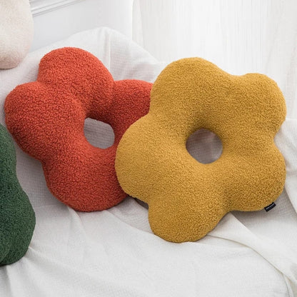 Coussins décoratifs en forme de fleur, orange et jaune, posés sur un canapé blanc