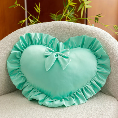 Coussin décoratif en forme de cœur, couleur menthe, avec volants et nœud, posé sur un canapé clair