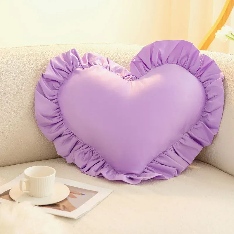 Coussin décoratif en forme de cœur, couleur lilas avec volants, posé sur un canapé beige
