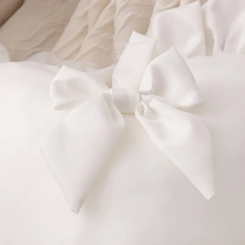 Coussin décoratif en forme de cœur, blanc avec un nœud en satin, posé sur un canapé élégant