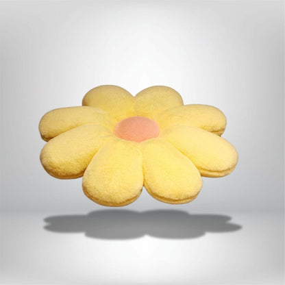 Coussin décoratif en forme de fleur, jaune avec un centre rose, posé sur un fond neutre