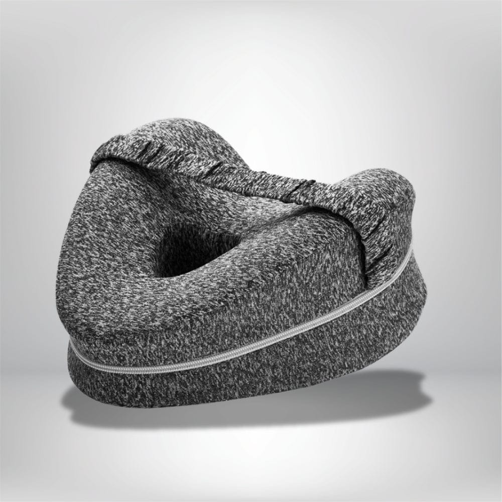 Coussin genoux en tissu gris chiné, forme ergonomique, posé sur une surface neutre, idéal pour un confort nocturne