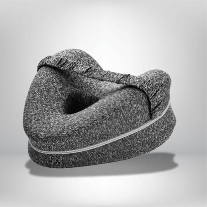 Coussin genoux en tissu gris chiné, forme ergonomique, posé sur une surface neutre, idéal pour un confort nocturne