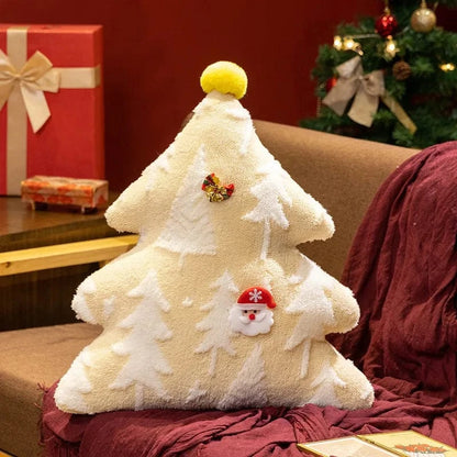 Coussin décoratif en forme de sapin, couleur crème avec motifs de sapins, posé sur un canapé marron
