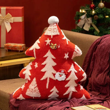 Coussin décoratif en forme de sapin rouge avec des motifs blancs, posé sur un canapé, ambiance festive et chaleureuse
