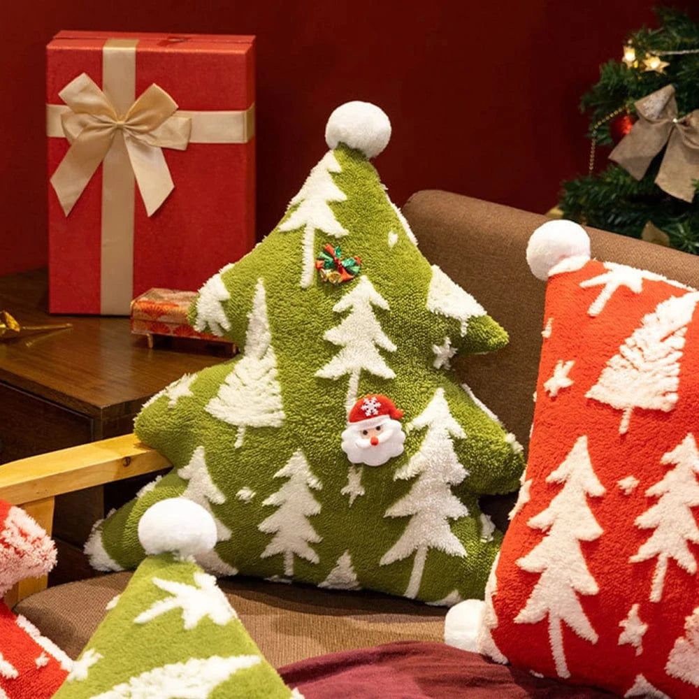 Coussin déco en forme d'arbre de Noël vert avec motifs blancs, posé sur un canapé confortable