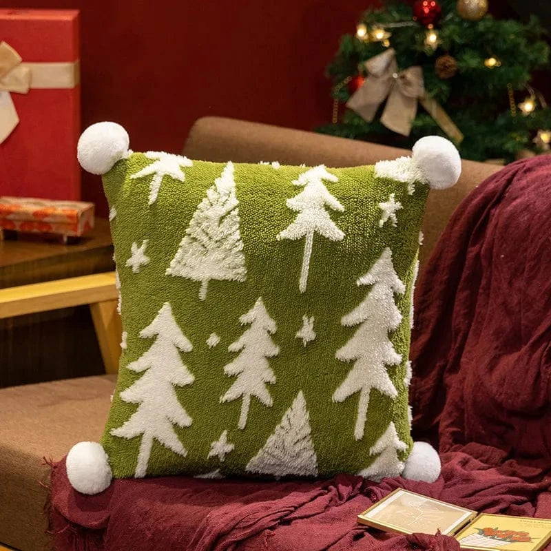 Coussin déco vert avec motifs d'arbres blancs, posé sur un canapé, apportant une touche festive à la décoration d'hiver