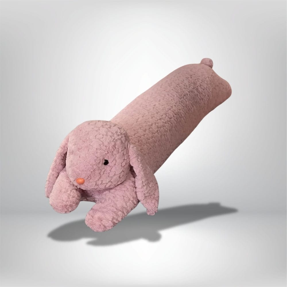 Coussin long en velours rose en forme de lapin, posé sur un fond neutre, idéal pour la décoration