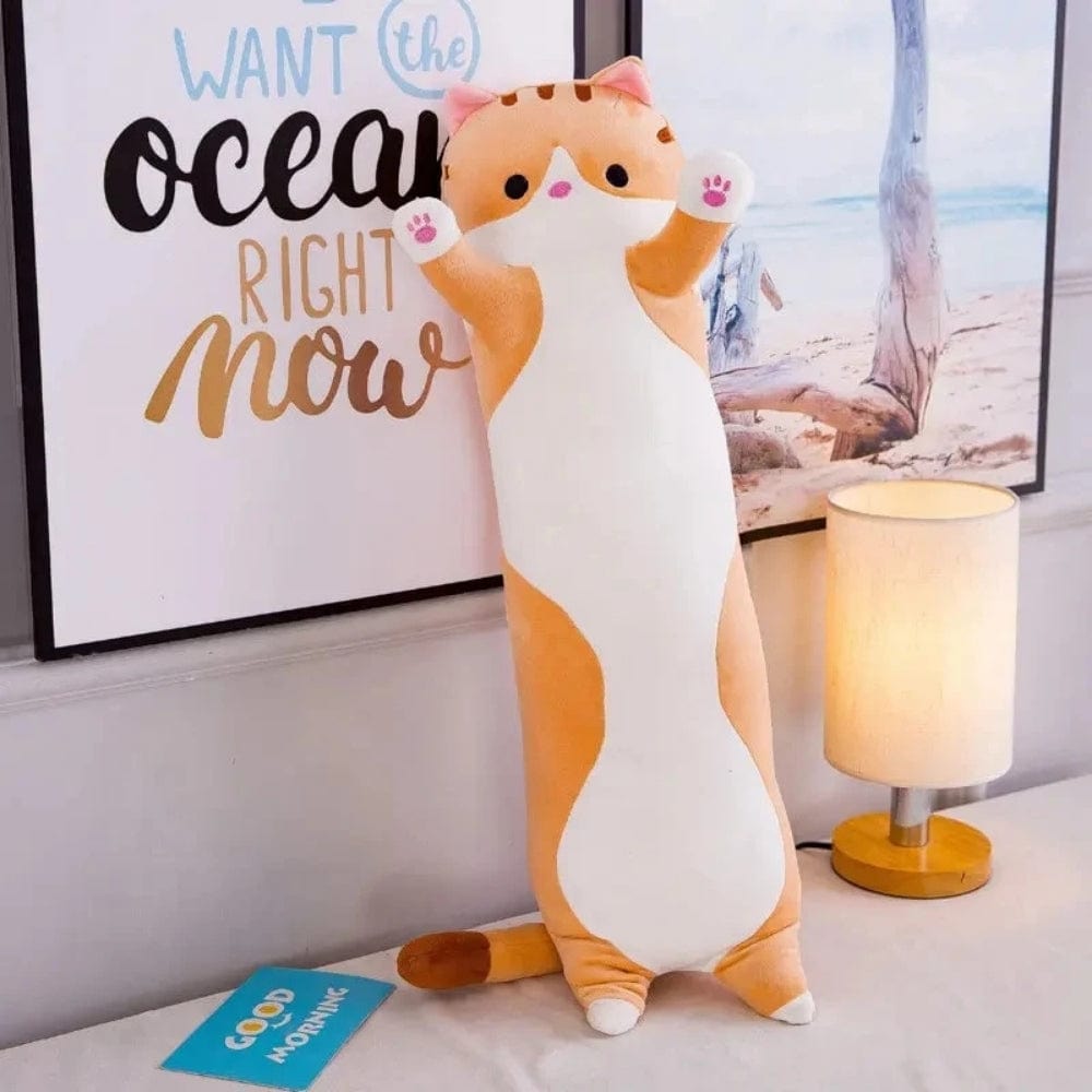 Coussin long en forme de chat, aux couleurs orange et blanc, décorant un lit avec une ambiance chaleureuse