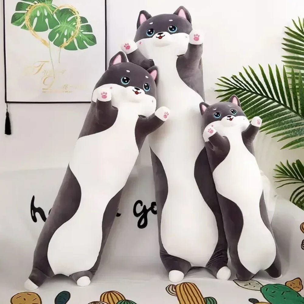 Coussins décoratifs en forme de chat, aux couleurs gris et blanc, posés sur un canapé moderne