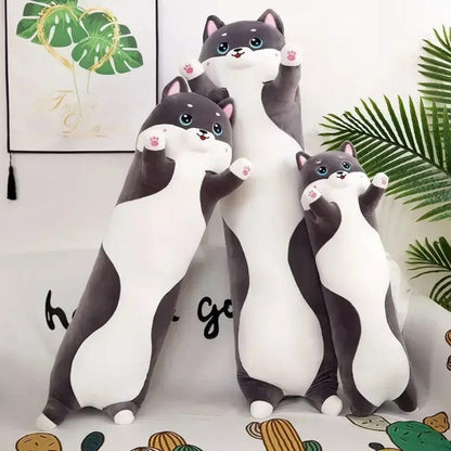 Coussins décoratifs en forme de chat, aux couleurs gris et blanc, posés sur un canapé moderne