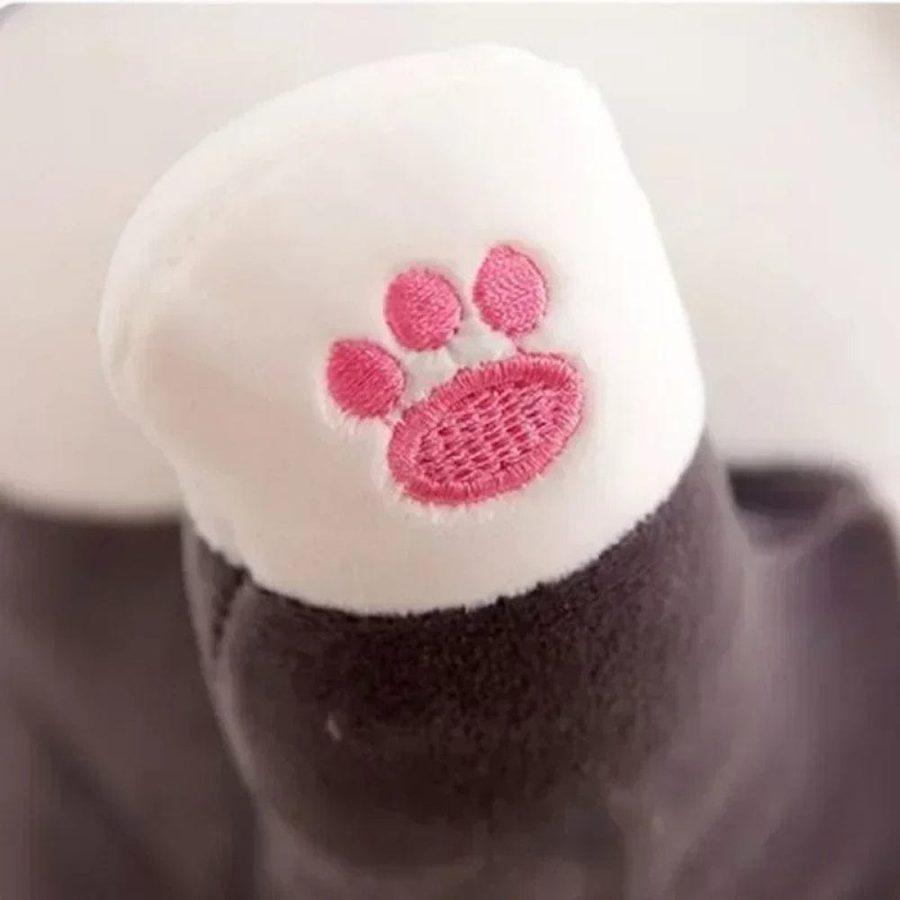 Coussin long en tissu doux avec motif de patte rose sur fond blanc, posé sur un canapé moderne