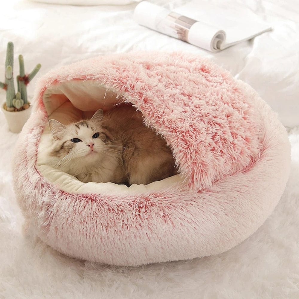 Coussin moelleux en fausse fourrure rose, posé sur un tapis blanc, avec un chat à l'intérieur