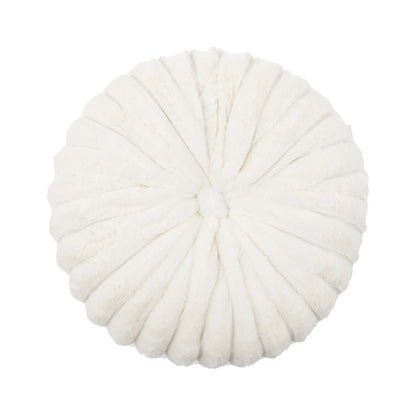 Coussin déco rond en velours blanc, avec des plis décoratifs, posé sur un canapé moderne
