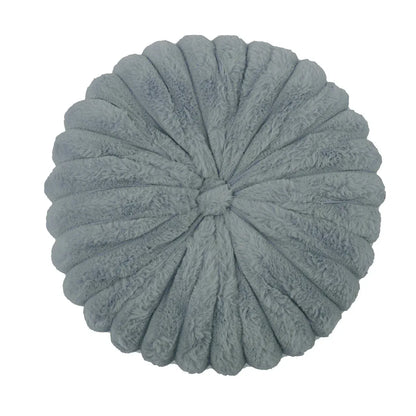 Coussin déco moelleux en velours gris, forme ronde avec des plis, posé sur un canapé