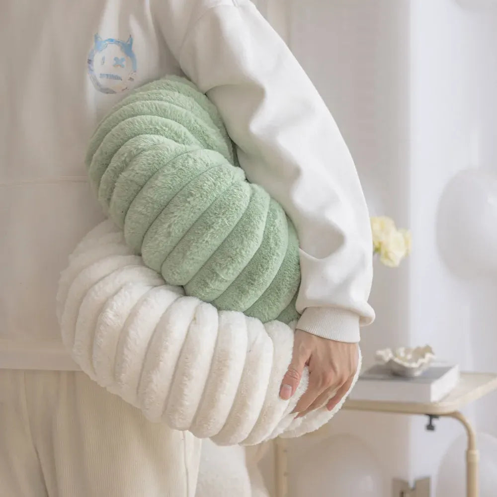 Coussins moelleux en velours vert et blanc, posés dans les bras d'une personne, décorant un intérieur moderne