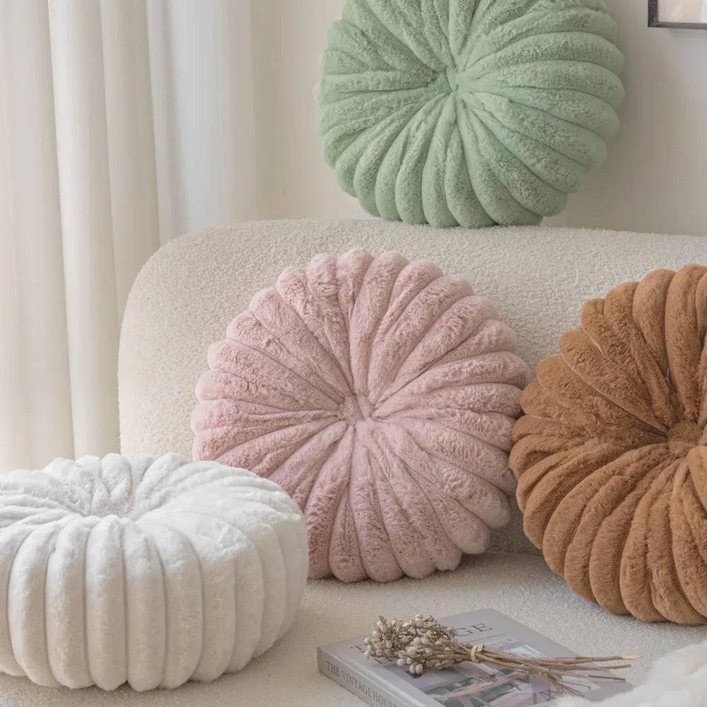 Coussins décoratifs moelleux en forme de fleur, aux couleurs pastel, disposés sur un canapé beige