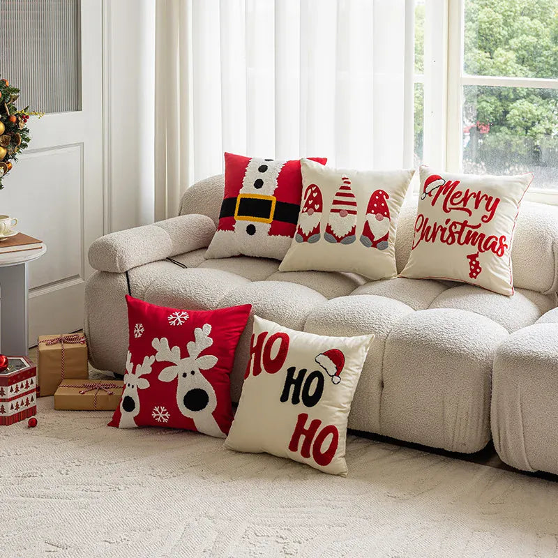 Coussins décoratifs aux motifs de Noël, rouge et blanc, sur un canapé beige dans un salon lumineux