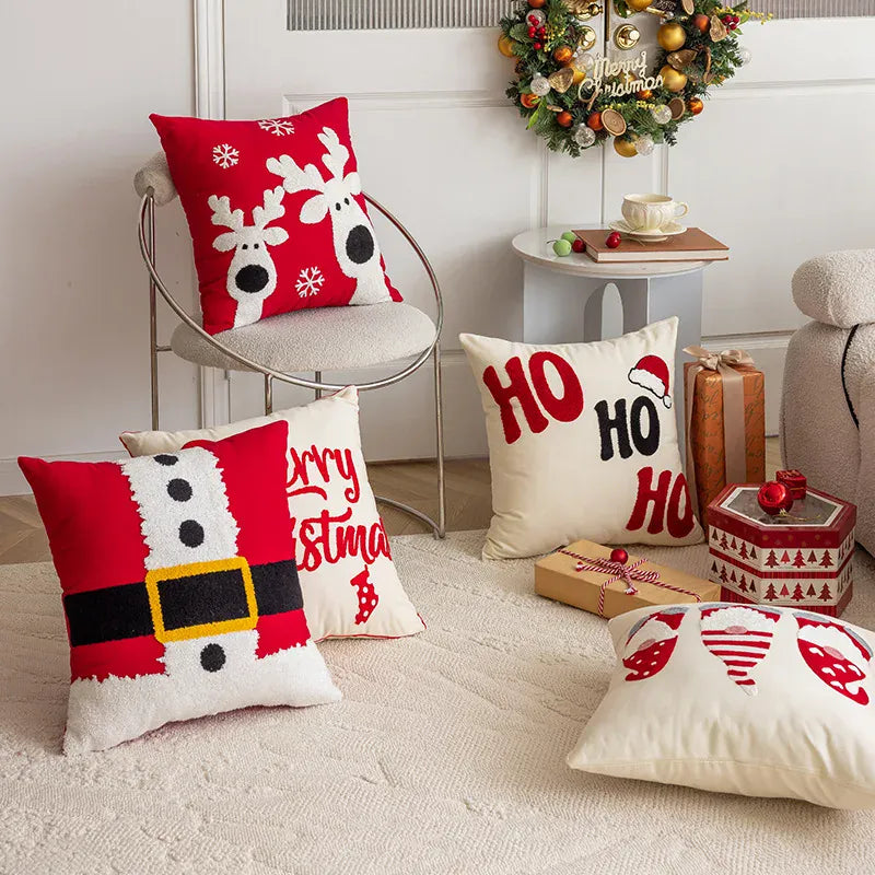 Coussins décoratifs aux motifs de Noël, rouges et blancs, disposés sur un tapis dans un salon chaleureux