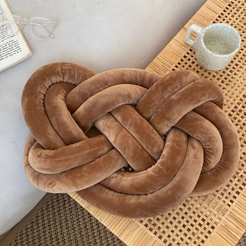 Coussin décoratif en velours marron en forme de nœud sur une table en bois