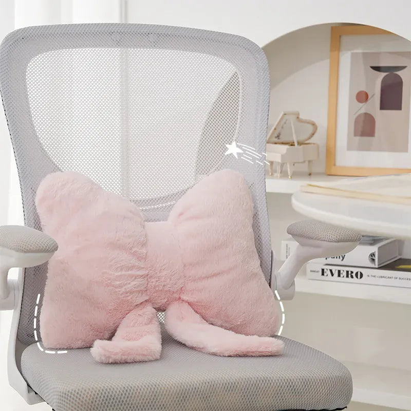 Coussin décoratif en forme de nœud papillon, en peluche rose, posé sur une chaise de bureau moderne