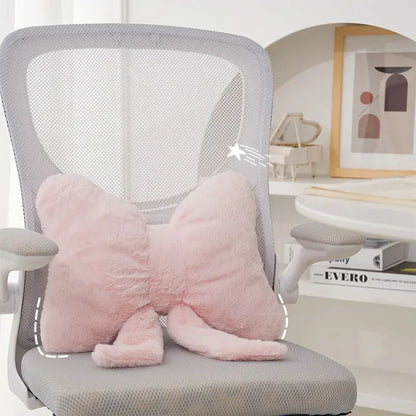 Coussin décoratif en forme de nœud papillon, en peluche rose, posé sur une chaise de bureau moderne