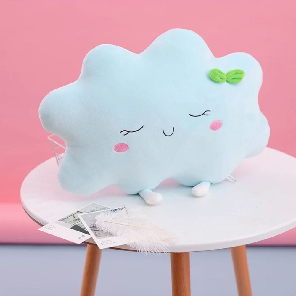 Coussin décoratif en forme de nuage bleu, doux, avec des détails souriants, posé sur une table en bois