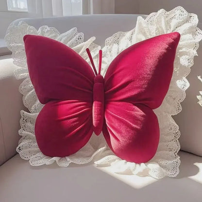 Coussin décoratif en forme de papillon rose avec des détails en dentelle, posé sur un canapé clair