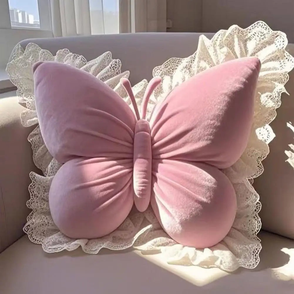 Coussin décoratif en forme de papillon rose avec une bordure en dentelle, posé sur un canapé