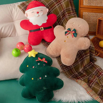 Coussins décoratifs en forme de Père Noël, bonhomme en pain d'épice et sapin, sur un canapé avec plaid