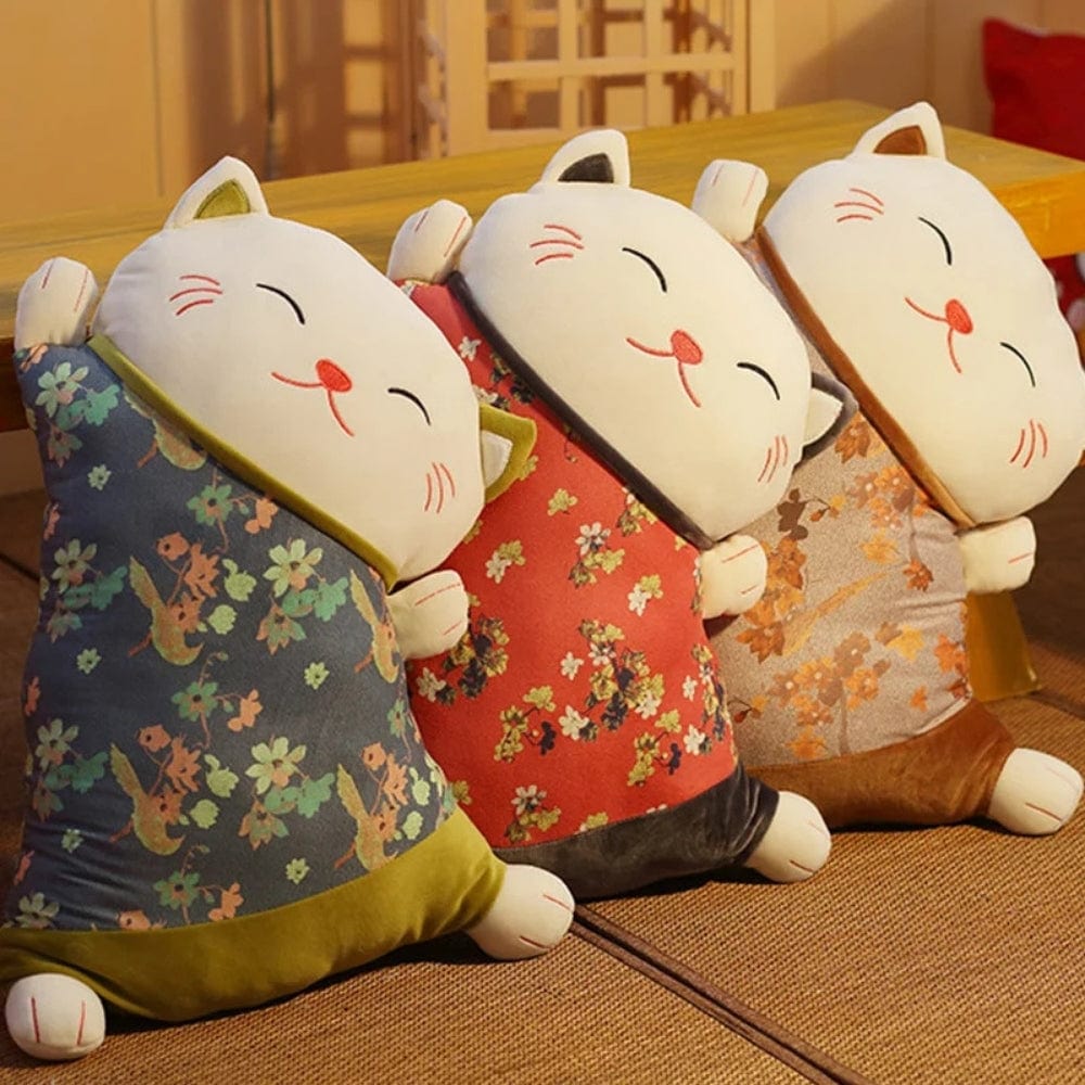 Trois coussins décoratifs en forme de chat aux motifs floraux, posés sur un sol en tatami