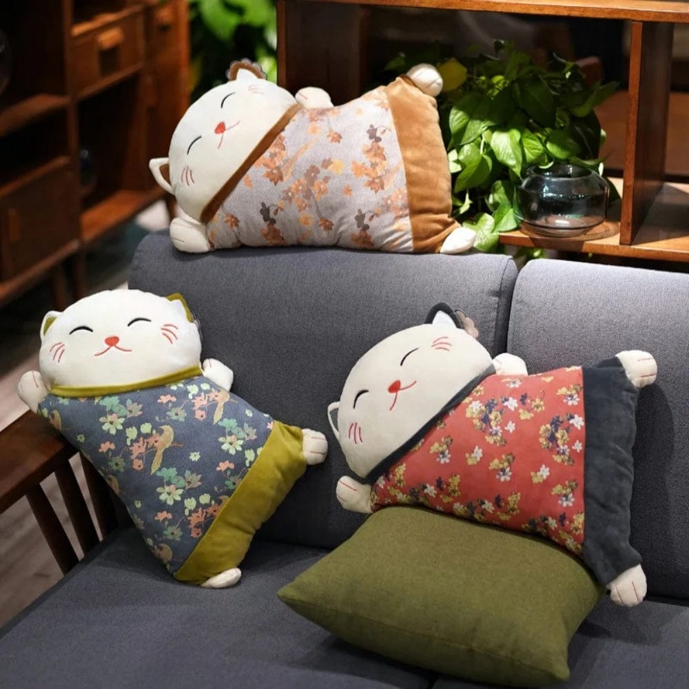 Trois coussins décoratifs en forme de chat avec des motifs floraux, posés sur un canapé gris