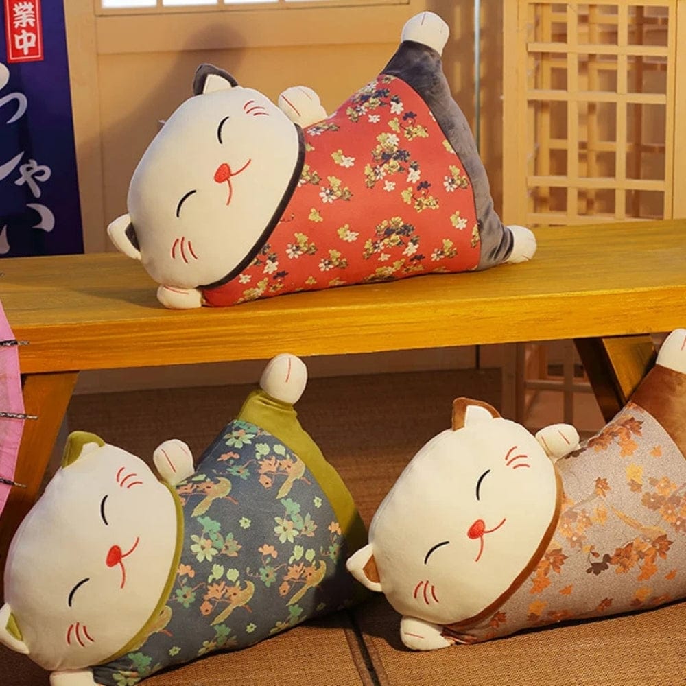 Trois coussins décoratifs en forme de chat aux motifs floraux, posés sur une table en bois