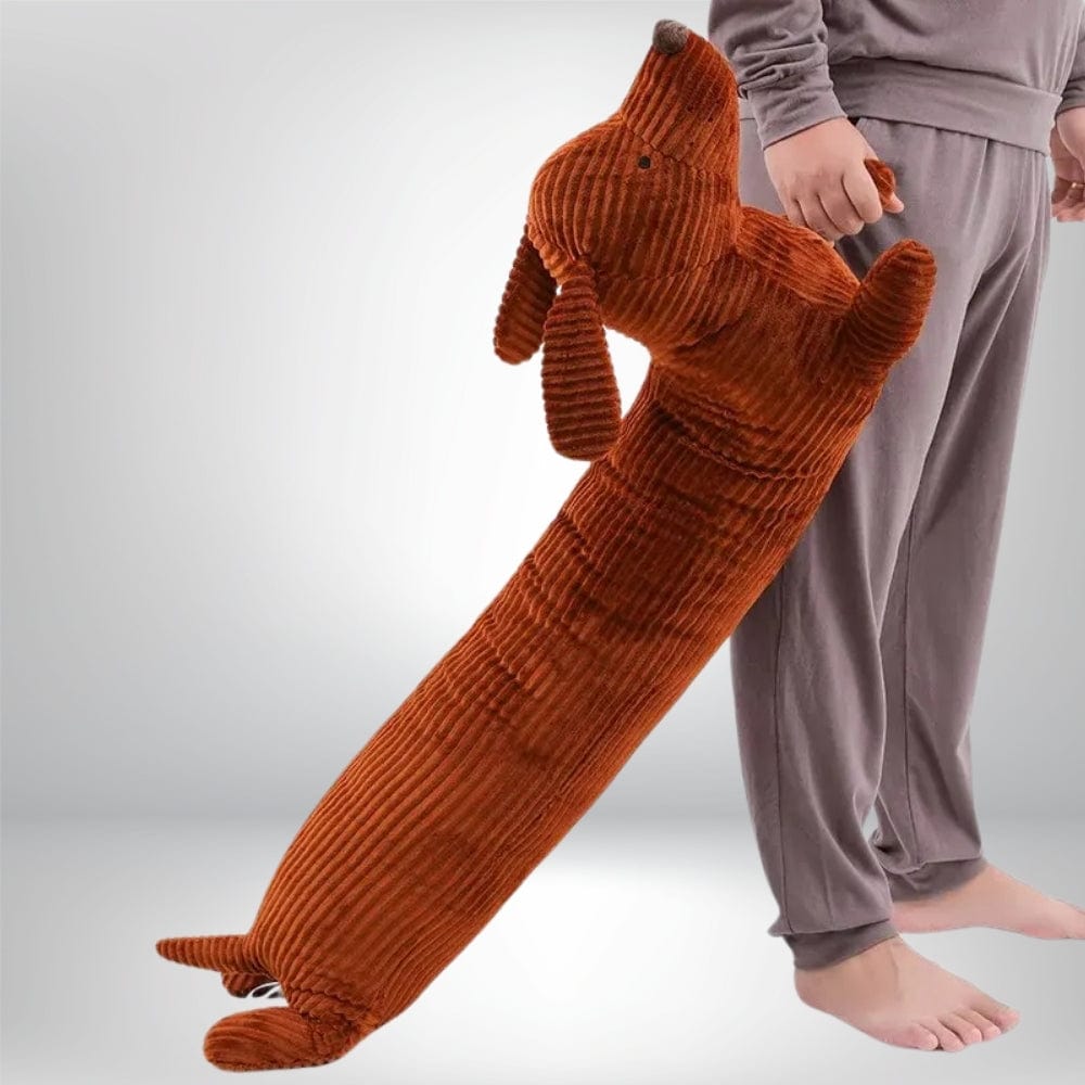 Coussin déco en forme de chien, en velours côtelé orange, posé près d'une personne en pyjama