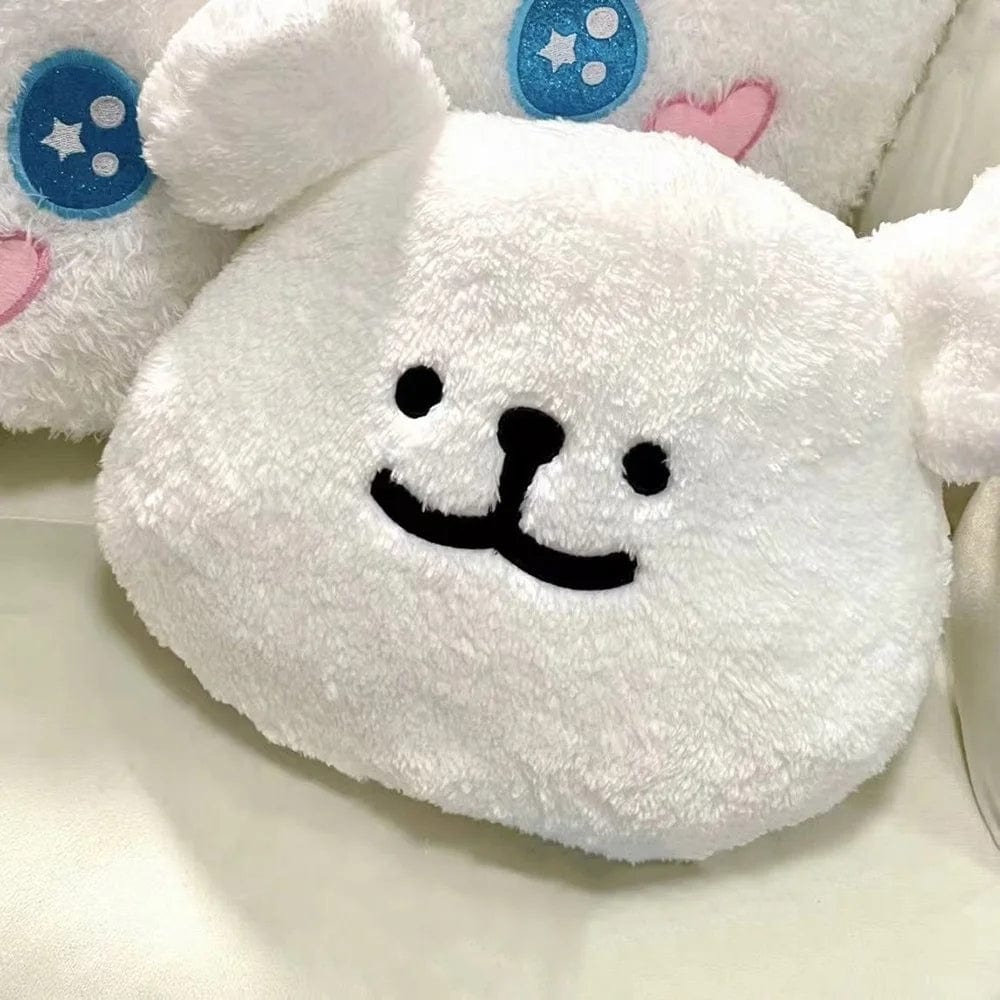 Coussin décoratif en forme de personnage blanc avec des oreilles, posé sur un canapé, ajoutant une touche ludique à la