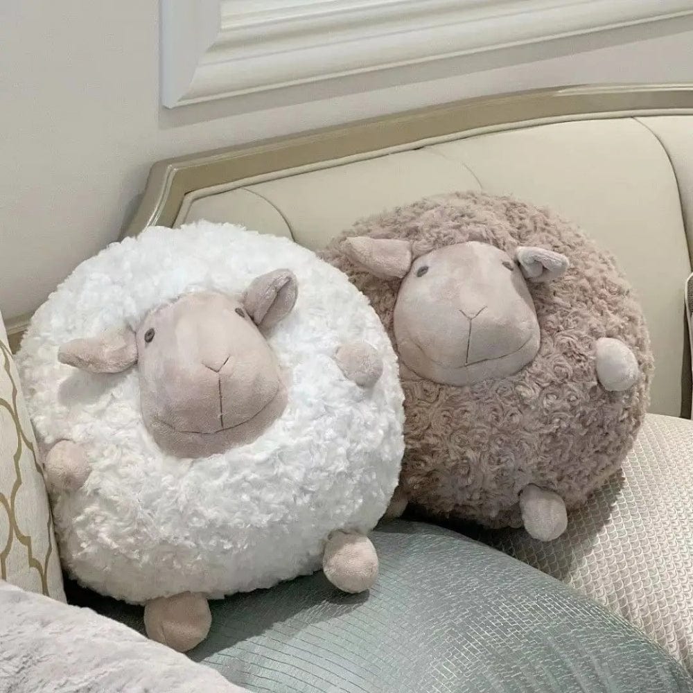 Coussins décoratifs en forme de mouton, en peluche blanche et beige, posés sur un canapé élégant