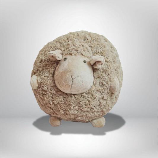 Coussin décoratif en forme de mouton, couleur beige avec texture douce, posé sur un fond neutre