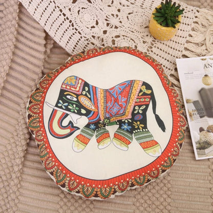 Coussin décoratif rond avec motif d'éléphant coloré sur fond crème, posé sur un tapis texturé