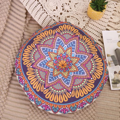 Coussin pouf de sol rond avec motifs colorés sur fond violet, posé sur un tapis beige dans un salon