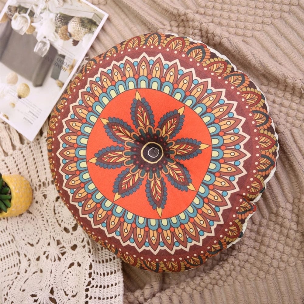 Coussin pouf rond aux motifs colorés orange et marron, posé sur un tapis texturé dans un salon