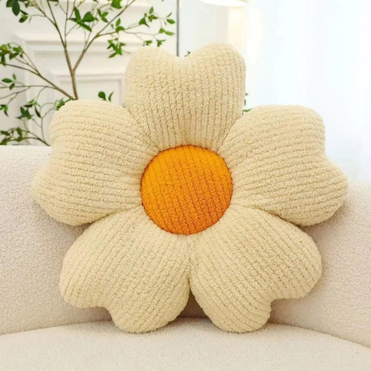 Coussin déco en forme de fleur beige avec un cœur orange, posé sur un canapé clair