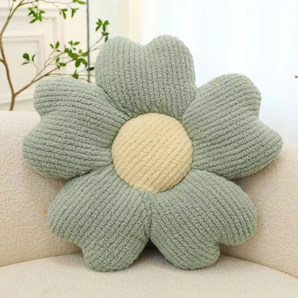 Coussin décoratif en forme de fleur, vert pastel et beige, posé sur une banquette douce et moderne