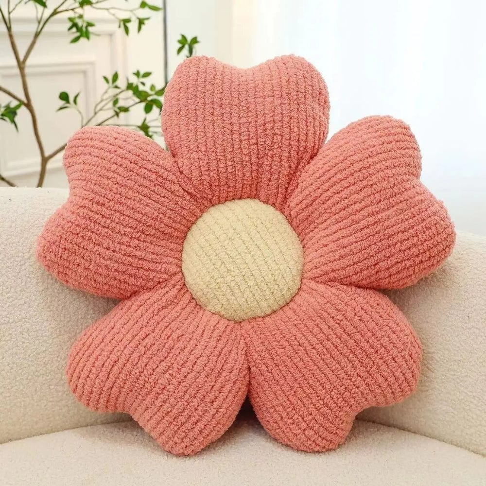 Coussin décoratif en forme de fleur, rose avec un centre beige, posé sur un canapé beige