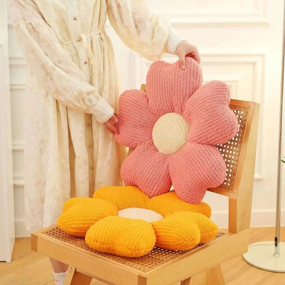 Coussins décoratifs en forme de fleurs, rose et orange, sur une chaise en bois dans un intérieur lumineux