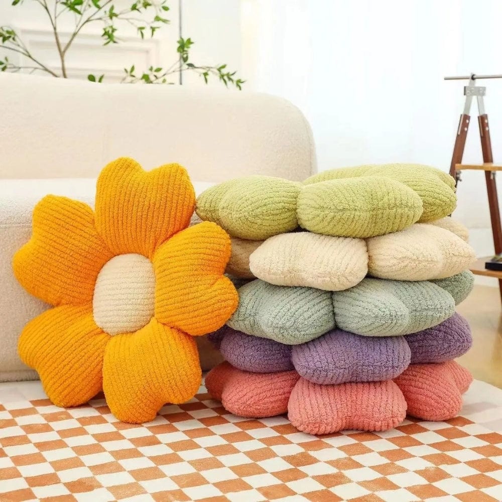 Coussins décoratifs en forme de fleurs aux couleurs pastel, posés sur un tapis à carreaux dans un salon lumineux